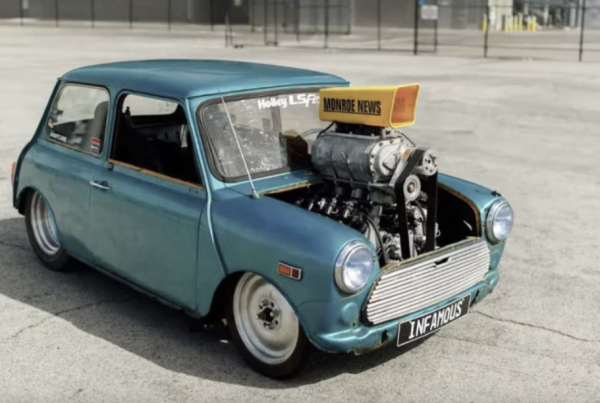 a large F1 engine in a classic, old, beat up blue mini coop